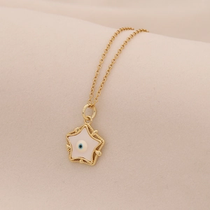 Macro detail of star pendant necklace featuring blue evil eye charm on gold chain