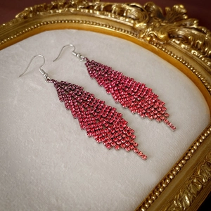 Detailed macro of crystal feather tassel earrings with red and pink gradient rhinestones