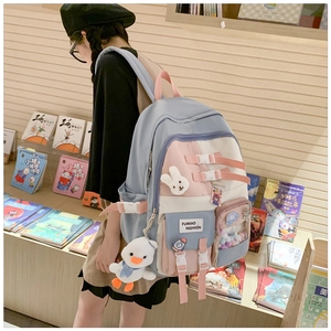 Detail of color-block school backpack with adjustable buckles and plush rabbit pendant