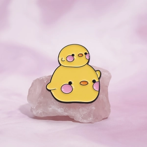 Cute cartoon yellow duck enamel pin badge on pink silk and crystal stone background