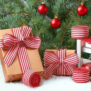 Red and white striped Christmas ribbon bow on craft gift box with tree background