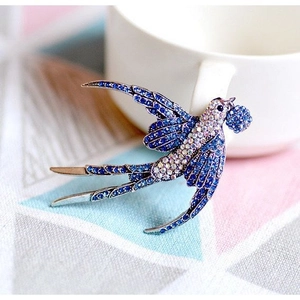 Spilla a forma di rondine blu e argento con strass scintillanti su una tazza bianca