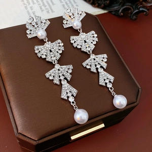 Close-up of sparkling rhinestone bow earrings with elegant pearl drops on jewelry box