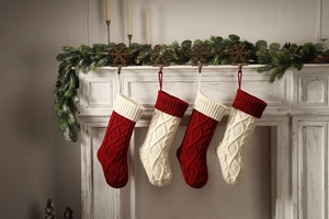 Close-up of red and cream knit Christmas stockings hanging on a white festive fireplace