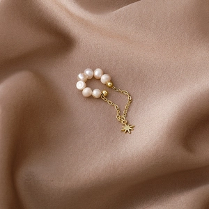 Elegant gold pearl ear cuff with star charm and tassel chain on a brown silk background