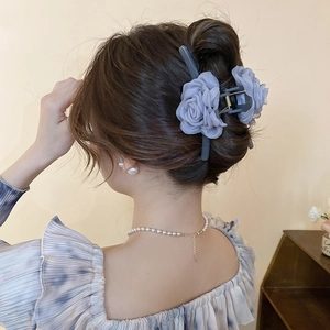 Detail einer grauen Chiffon-Blumen-Haarklammer am Dutt mit elegantem Perlen-Schmuck