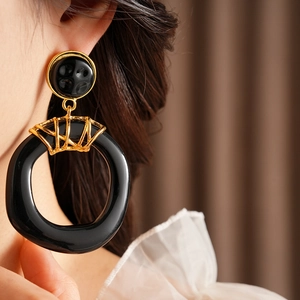 Gros plan de boucles d'oreilles vintage en résine noire portées par un mannequin avec métal