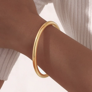 Minimalist gold stainless steel bangle worn on wrist with a cozy white sweater detail