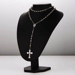 Two-tone silver and gold beaded rosary necklace with a white cross on a display bust
