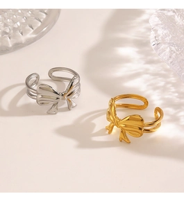 Detail of 18K gold and silver bow rings with adjustable open band and polished finish