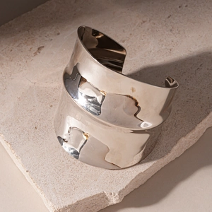Macro shot of polished silver wide cuff bracelet with irregular wavy texture on stone