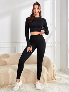 Détail de l'ensemble de yoga noir avec haut court à manches longues et legging taille haute