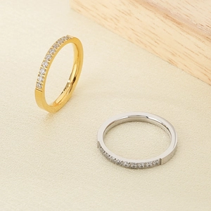 Close-up of gold and silver half eternity rings with clear zircons on a beige background