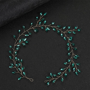 Detail of vintage gold wire headband featuring marquise cut emerald green rhinestones