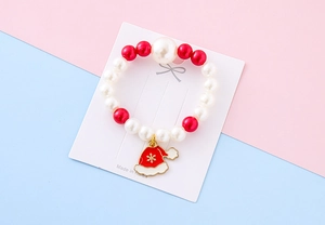 Detail of children's Christmas bracelet with red pearls and enamel Santa hat charm