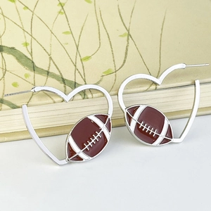 Silver heart hoop earrings featuring brown enamel American football charms on a book
