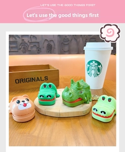 Miniature crocodile and dinosaur tooth game toys with golden keychains on a wooden desk