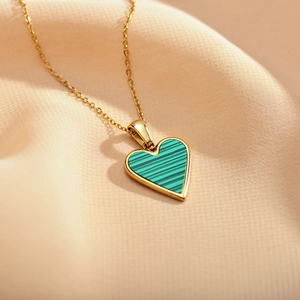 Elegant gold heart necklace with malachite green stripes on silk background