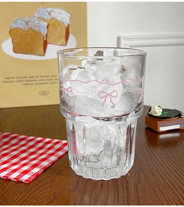 Detail of transparent glass cup with pink bow patterns and ice cubes inside