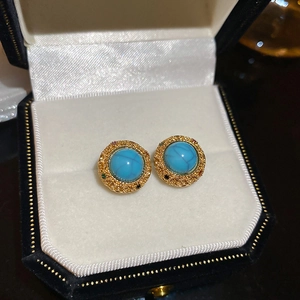 Detail shot of vintage 18k gold earrings with turquoise stones in a black velvet box