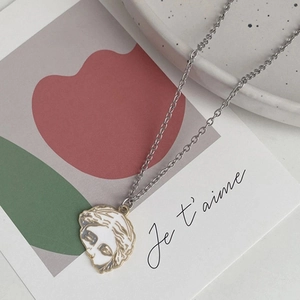 Macro shot of silver Venus portrait pendant on thin titanium chain against art card