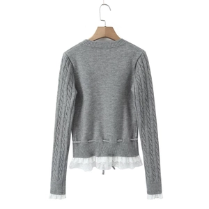 Detailed view of grey cable knit sweater with white floral lace trim on cuffs and hem