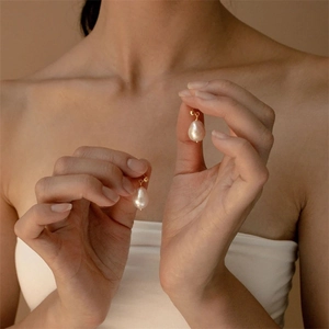 Baroque freshwater pearl earrings with gold stainless steel hooks on model's hand