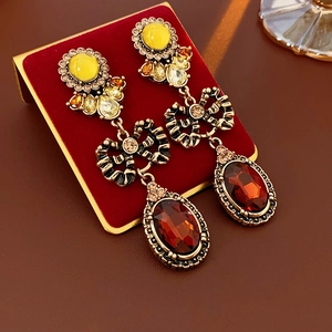 Close-up of vintage gold-tone bow earrings with crimson oval and amber drop gemstones