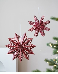 Close-up of red 3D paper star and snowflake ornaments with glitter and laser cut detail