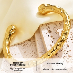 Detail view of 18K gold plated C-shaped bangle with irregular hammered texture on titanium steel