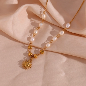 Macro detail of freshwater baroque pearl and golden bead chain with sun pendant charm