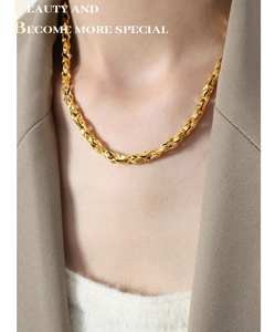 Close-up of golden twisted rope chain necklace worn over a stylish brown blazer