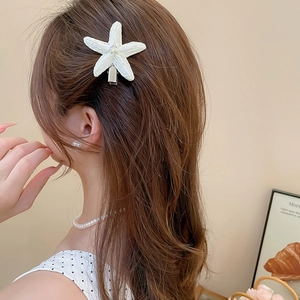 Détail d'une pince à cheveux étoile de mer en raphia blanc avec strass sur modèle