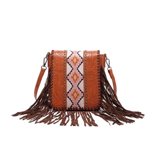 Detail of bohemian leather crossbody bag with embossed patterns, studs and long tassels