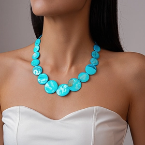 Detail of layered bright blue shell disc necklace on model with bohemian resort style