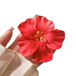 Vibrant red hibiscus flower hair clip with yellow stamen on white background