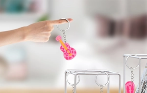 Detail of pink PVC guitar and cowgirl boot keychains with silver metal rings