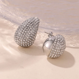 Detail of silver drop earrings with asymmetrical rhinestone inlay and polished finish