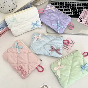 Flat lay of colorful quilted bow makeup bags in pink, purple, blue, white, and green