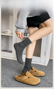 Detail of dark gray ribbed cotton crew socks styled with camel suede buckle mule shoes