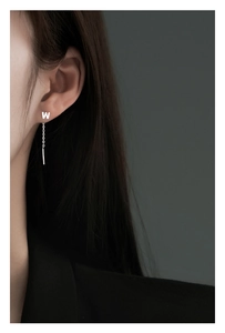 Close-up of S999 sterling silver ear threader with W letter charm worn on model