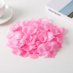 Pink silk artificial rose petals for wedding decoration arranged on a white surface