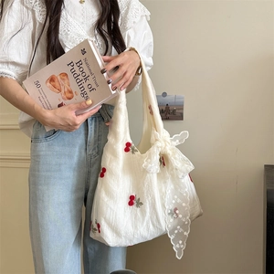 Detail of white cotton tote bag with cherry embroidery and delicate lace bow accents