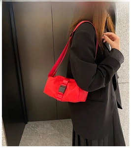 Red Oxford fabric crossbody bag shown on a model with a black buckle and wide strap
