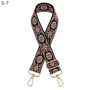 Close-up of ethnic style adjustable bag strap with pink and black floral woven patterns