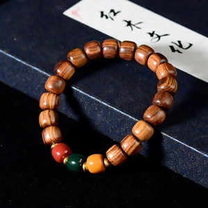 Macro detail of polished rosewood beads with red, green, and yellow decorative spacers