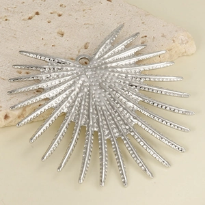 Macro view of 304 stainless steel sunburst charm on a textured beige stone background