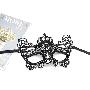 Close-up of black lace masquerade mask with crown design and ribbon ties on a desk