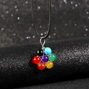Detailed view of colorful seven-chakra stone pendant on a silver hexagram woven base