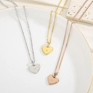 Détail de pendentifs cœur en argent, or et or rose avec strass posés sur un plateau